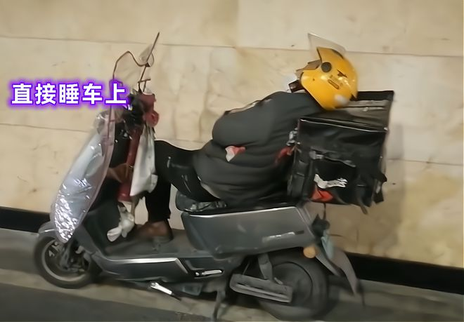 一名外卖小哥竟盖着被子和送外卖时穿的冲锋衣，睡在自己的电动车上