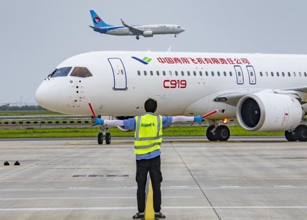 C919飞机进行功能和可靠性科目试飞，地面引导人员将飞机引导停入机位