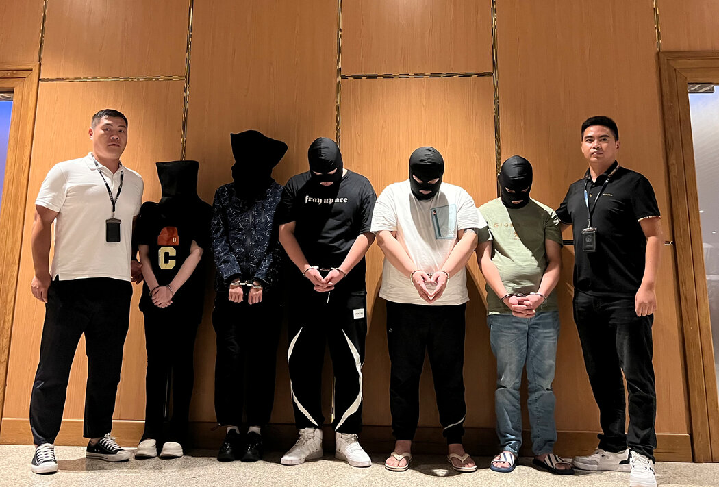仰光国际机场，两名警察中间是五名被控电信和网络诈骗的嫌疑人
