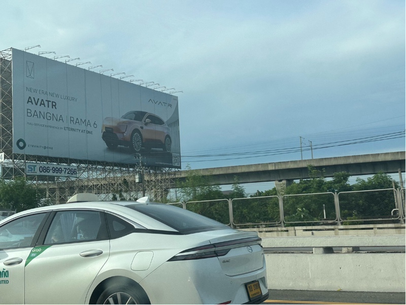 机场通往市区的高速公路两旁，树立着上汽MG、比亚迪、长安阿维塔等多家车企的户外广告 ...
