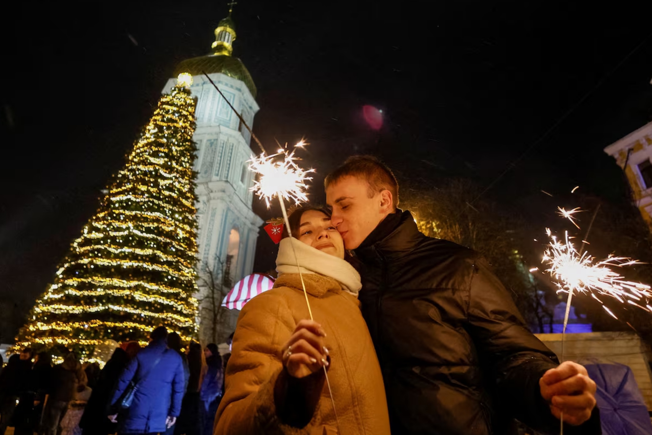 在乌克兰基辅，一对情侣在新年庆祝活动中于圣诞树旁拥吻